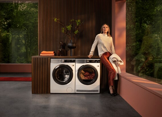 Woman standing next to washing machine and dryer unit..