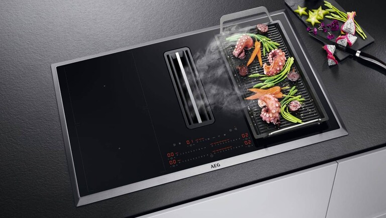 Μαγείρεμα φαγητού σε σχάρα plancha τοποθετημένη σε εστία AEG.